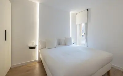 a white bed in a white room with a window at Stay U-nique Apartments Villarroel II in Barcelona