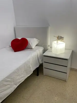 a bed with a red heart pillow and a night stand at Apartament a Arenys de Mar in Arenys de Mar
