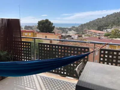 a hammock on a balcony with a view of a city at Apartamento con vistas al mar in Castelldefels