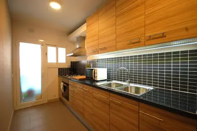 a kitchen with a sink and black tiles on the wall at Lets Holidays New Flat Beachfront In Castelldefels in Castelldefels