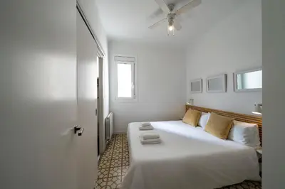 a bedroom with a large white bed with a ceiling fan at Habitat Apartments Vila in Barcelona