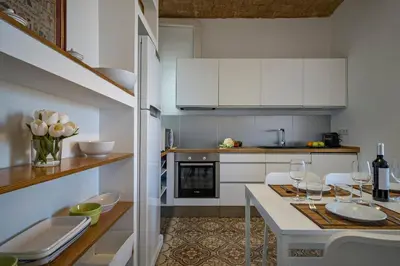 a kitchen with white cabinets and a table with wine glasses at Habitat Apartments Vila in Barcelona