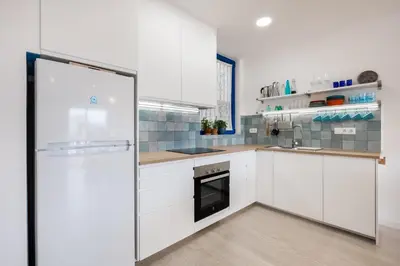 a kitchen with white cabinets and a refrigerator at Apartamento artístico Vilanova in Vilanova i la Geltrú