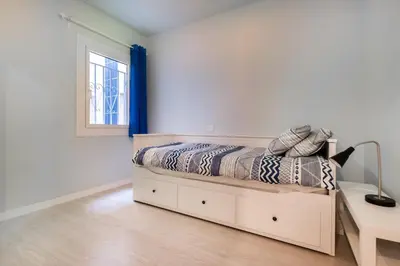 a white bedroom with a bed and a window at Apartamento artístico Vilanova in Vilanova i la Geltrú