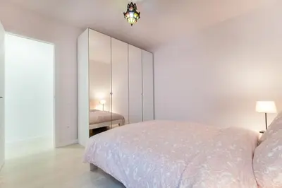 a white bedroom with a bed and a mirror at Apartamento artístico Vilanova in Vilanova i la Geltrú