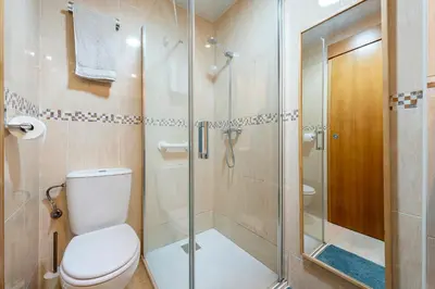 a bathroom with a toilet and a glass shower at Hauzify I Casa Ribera in Cunit