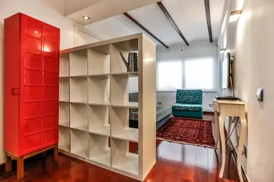 a room with a red book shelf and a chair at Montroig Mar in Sitges