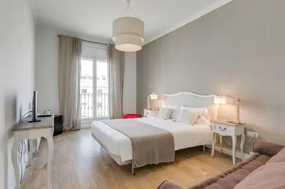 a white bedroom with a bed and a couch at Rambla Catalunya Sky in Barcelona