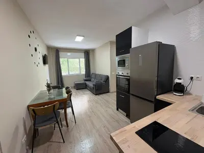 a kitchen and living room with a table and a refrigerator at FELIPE II Apartment in Barcelona