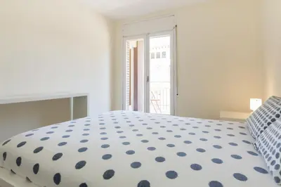 a white bedroom with a large bed with blue polka dots at Pubone AT Barberà del Valles in Barbera del Valles