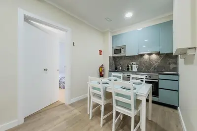 a kitchen with blue cabinets and white stools at Habitación 1 NOU DE LA RAMBLA in Barcelona
