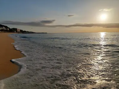 a beach with the sun rising over the ocean at Oasis cerca de Barcelona in Sant Vicenç de Montalt