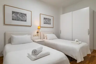 two beds in a room with white sheets and towels at Stay U-nique Apartment Creu Coberta II in Barcelona