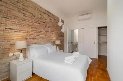 a bedroom with a white bed and a brick wall at Stay U-nique Apartment Creu Coberta II in Barcelona