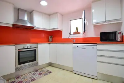 a kitchen with white cabinets and a red wall at Apartment in the heart of Barcelona in Barcelona