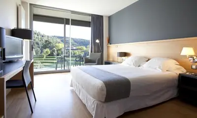 a hotel room with a bed and a desk with a television at Hotel Món Sant Benet in Sant Fruitos de Bages