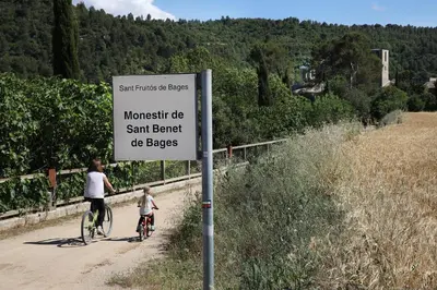 a sign with two people riding bikes on a dirt road at Hotel Món Sant Benet in Sant Fruitos de Bages