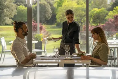 a woman waiter serving people at a table in a restaurant at Hotel Món Sant Benet in Sant Fruitos de Bages