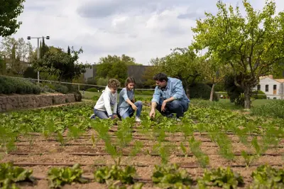 a man and two children playing in a garden at Hotel Món Sant Benet in Sant Fruitos de Bages