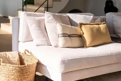 a white couch with white pillows and a basket at Infinity House in Cabrera de Mar