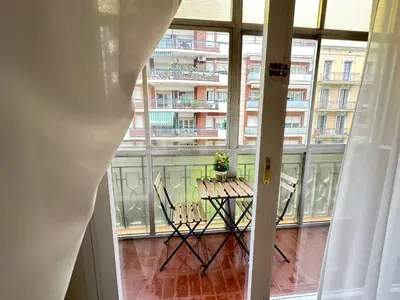 a table and chairs in a room with a large window at Apartamento en Viladomat in Barcelona