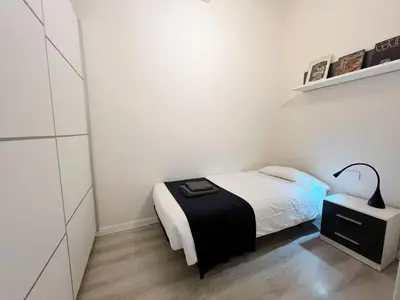 a small white bedroom with a bed and a lamp at Bogatell Playa Apartment in Barcelona