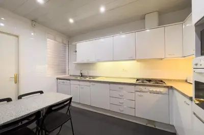 a kitchen with white cabinets and a table with chairs at Gran Vía Sun in Barcelona