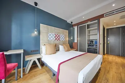 a bedroom with a large bed and a red chair at Boutique Hostemplo Sagrada Familia in Barcelona