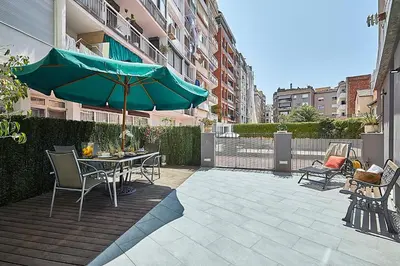a patio with a table and a green umbrella at BBarcelona Brusi Flat in Barcelona