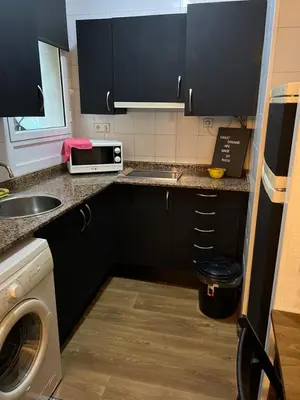 a kitchen with black cabinets and a sink and a microwave at Loft Center Rambla in Barcelona