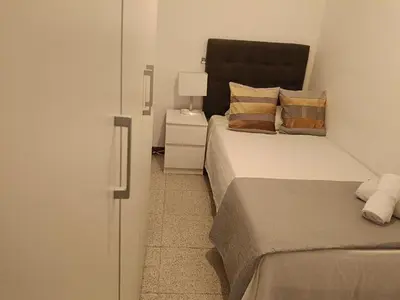 a bedroom with two beds and a night stand with a lamp at Habitación individual acogedora in Barcelona