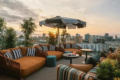 a rooftop patio with couches and an umbrella at The Social Hub Barcelona Poblenou Extended Stay in Barcelona
