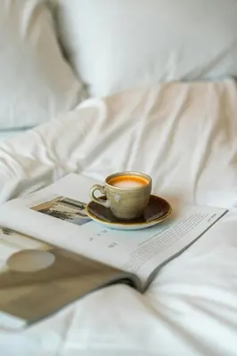 a cup of coffee and a book on a bed at The Social Hub Barcelona Poblenou Extended Stay in Barcelona