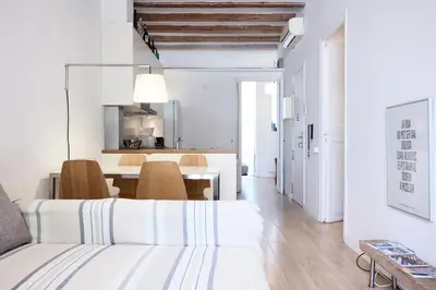 a white living room with a white couch and a table at Sunny apartment on the square in Barcelona