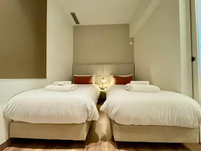 a room with two beds with white sheets and orange pillows at MODERN ELEGANCE by MyRentalHost in Barcelona