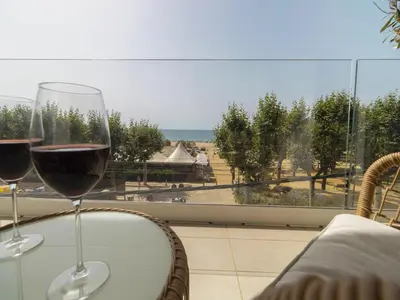 two glasses of wine sitting on a table in front of a window at Seafront Apartment in Calella with Beach Access in Calella