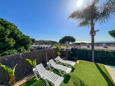 a row of white lawn chairs in a yard at Stylish villa with saltwater pool in Caldes d'Estrac