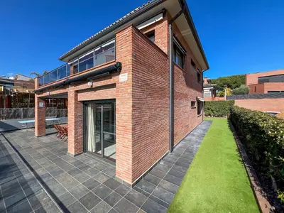 a brick house with a patio and grass at Stylish villa with saltwater pool in Caldes d'Estrac