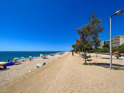 a beach with people laying on the sand and the ocean at Beachfront gateway in Pineda de Mar in Pineda de Mar