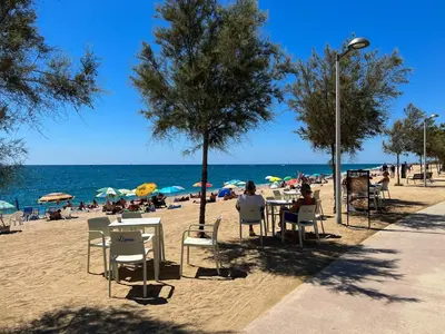 a group of people sitting at tables on a beach at Beachfront gateway in Pineda de Mar in Pineda de Mar