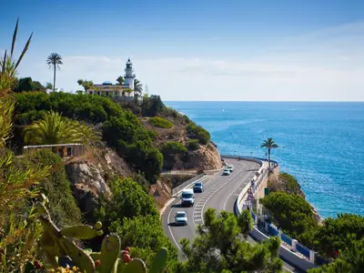 a road with a lighthouse on a hill next to the ocean at Apartment in Calella near the Beach in Calella