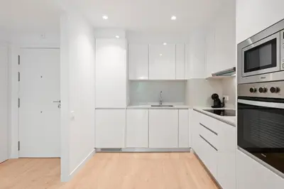 a white kitchen with a sink and a microwave at Monthly 32 Nights 1BR Pools Parking in Barcelona