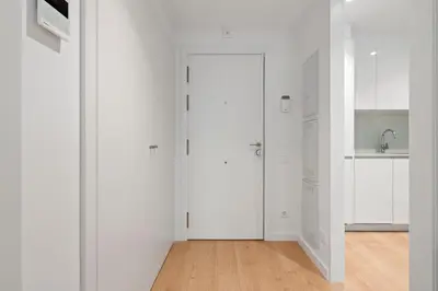 a white kitchen with white cabinets and a door at Monthly 32 Nights 1BR Pools Parking in Barcelona