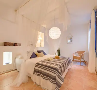 a white bedroom with a bed with a canopy at Blue Home in Sitges