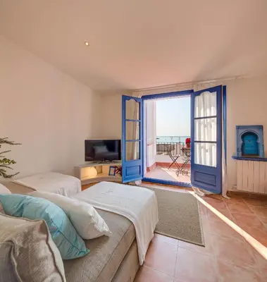 a living room with two beds and a large window at Blue Home in Sitges