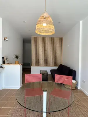 a living room with a glass table and two pink chairs at Son Roca Ribes Guest House in Sant Pere de Ribes