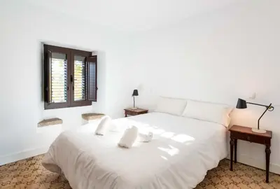 a white bed in a room with a window at Unique 16th-Century Masia, Pool & Private Events in Barcelona