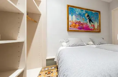 a bedroom with two beds and a painting on the wall at Provenza Flat in Barcelona