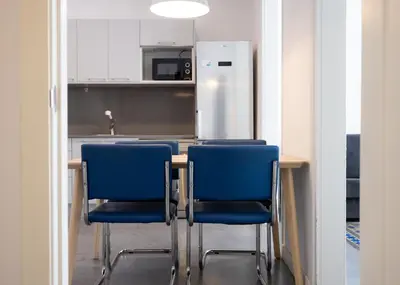 a kitchen with a table with blue chairs and a refrigerator at Stay U-nique Apartment Republica Argentina in Barcelona