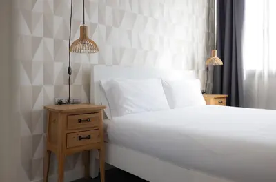 a bedroom with a white bed and a nightstand with two lamps at Stay U-nique Apartment Republica Argentina in Barcelona